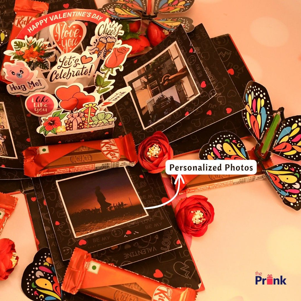 Valentine’s Day explosion box with personalized photos, colorful butterfly cutouts, red roses, and KitKat bars, creating a festive, loving ambiance.
