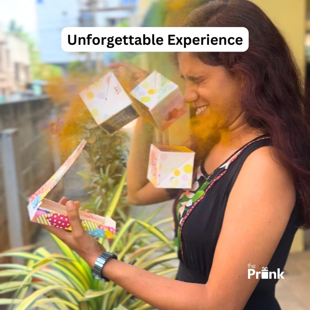 A woman, smiling with closed eyes, opens a colorful box that releases vibrant orange powder and cubes into the air. The mood is joyful and surprising.