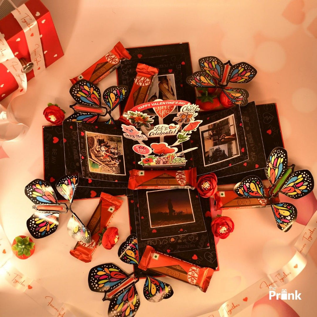 Colorful Valentine's display of three layered open box with chocolate bars, butterfly cutouts, and romantic cards. Bright, festive, and warm atmosphere conveying celebration.