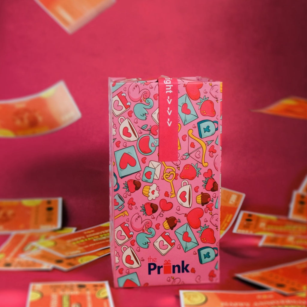 Gift box with playful pink and blue cartoon hearts, strawberries, and flamingos. Red ribbon on top. Orange cards flutter around on red background.