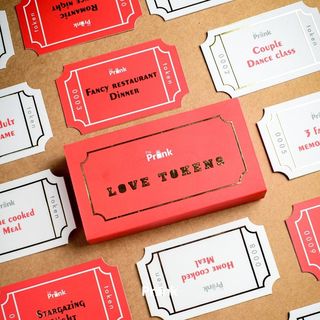A collection of red and white love tokens on a brown surface, featuring romantic activities like "Fancy Restaurant Dinner" and "Couple Dance Class."