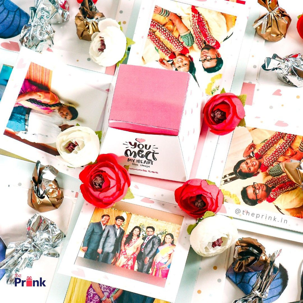 A decorative gift box with "You melt my heart like these" is surrounded by colorful photos, red and white flowers, and wrapped candies, creating a romantic, festive feel.