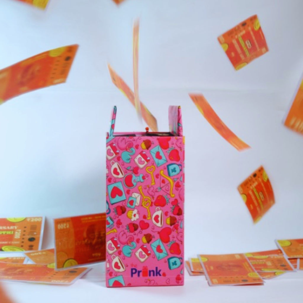 Pink box with colorful heart and key designs, surrounded by floating orange play money. The scene conveys a playful and whimsical tone.