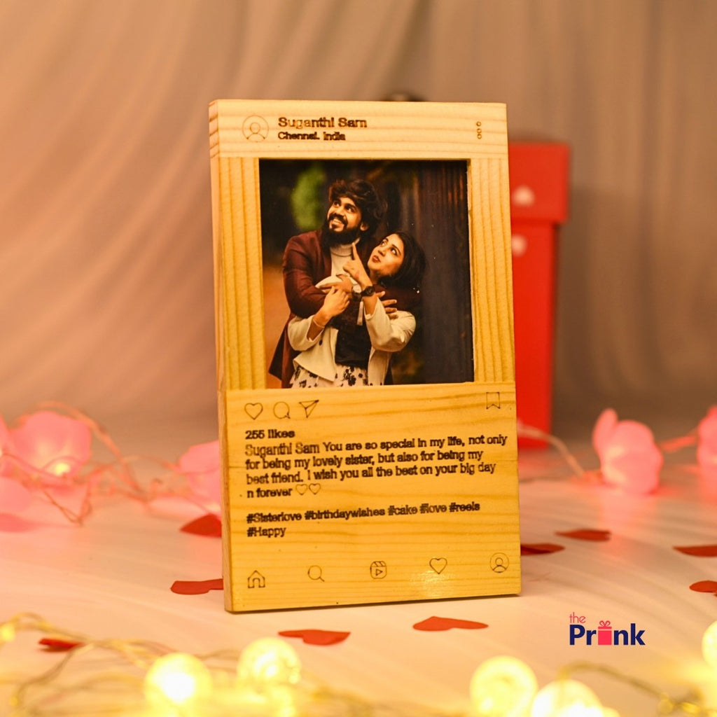 A wooden photo frame with a social media theme displays a happy couple embracing. Soft, warm lighting and pink heart-shaped lights add a romantic ambiance.
