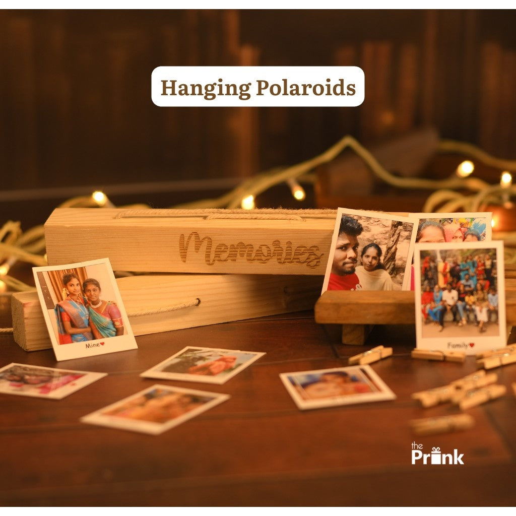 Wooden blocks with "Memories" engraved, surrounded by scattered Polaroid photos on a table. Warm fairy lights create a cozy, nostalgic ambiance.