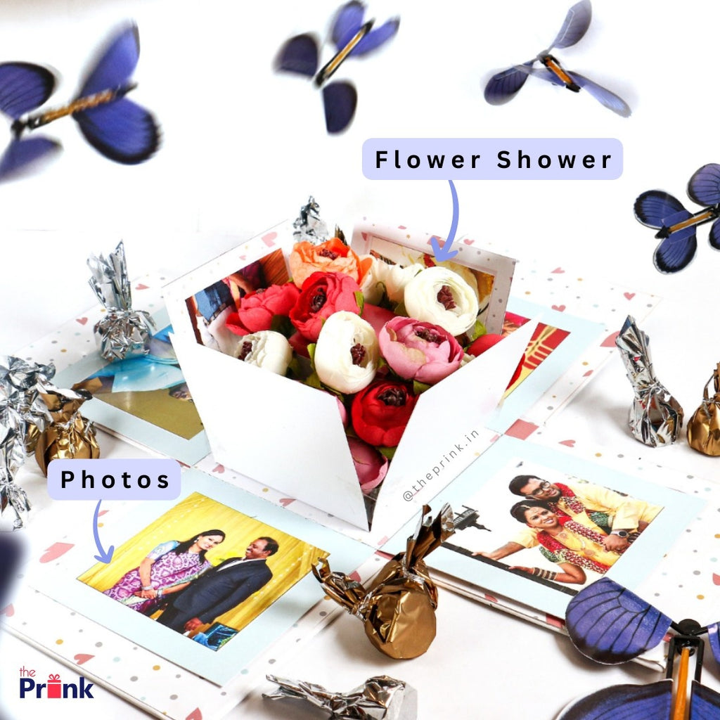 The image shows a gift box with colorful flowers and photos, surrounded by blue butterflies. Captions read "Flower Shower" and "Photos," creating a joyful mood.
