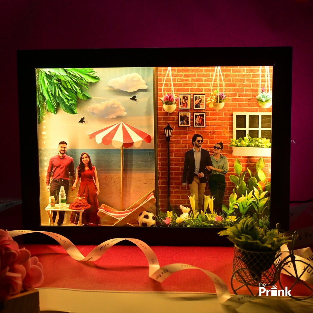 Shadow box divided into two scenes: Left, a couple at a beach with seashells and an umbrella. Right, a couple in a garden by a brick wall. Warm, joyful mood.