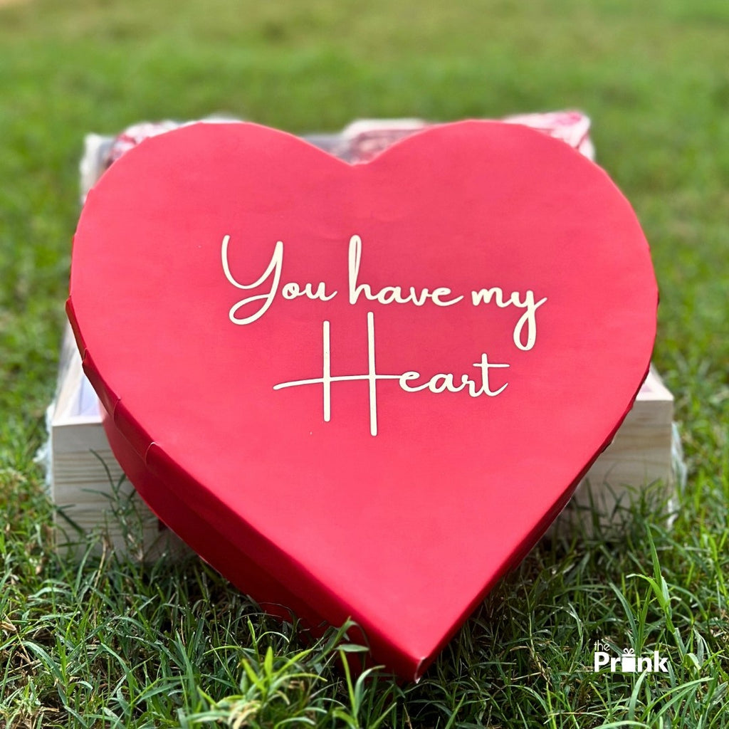 A red heart-shaped box with the words "You have my Heart" written in white sits on green grass, conveying a romantic and heartfelt message.