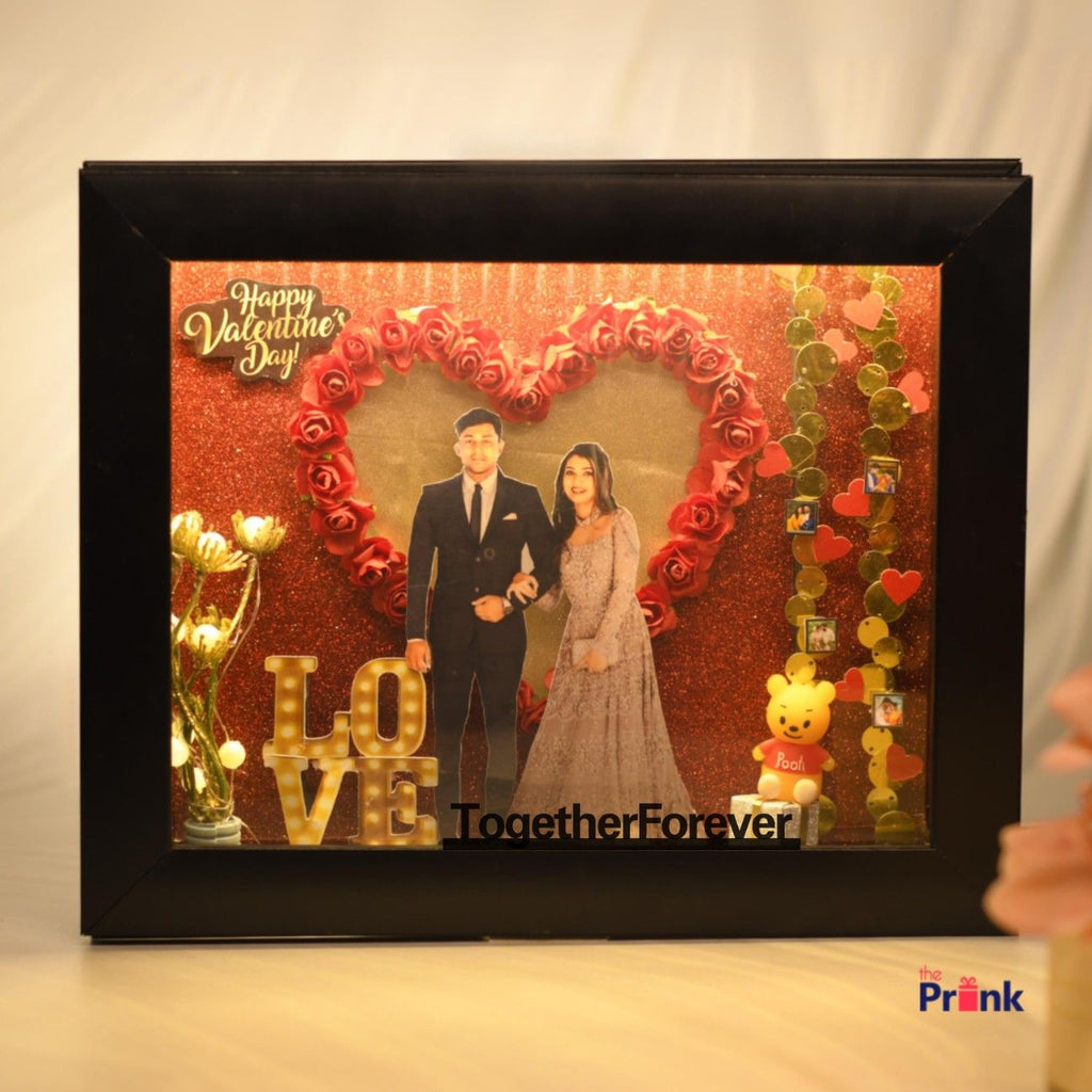 Framed 3D Box with a couple cutout against a glittery red background. Red rose heart, "LOVE" letters, Valentine's message, and teddy bear add romance.