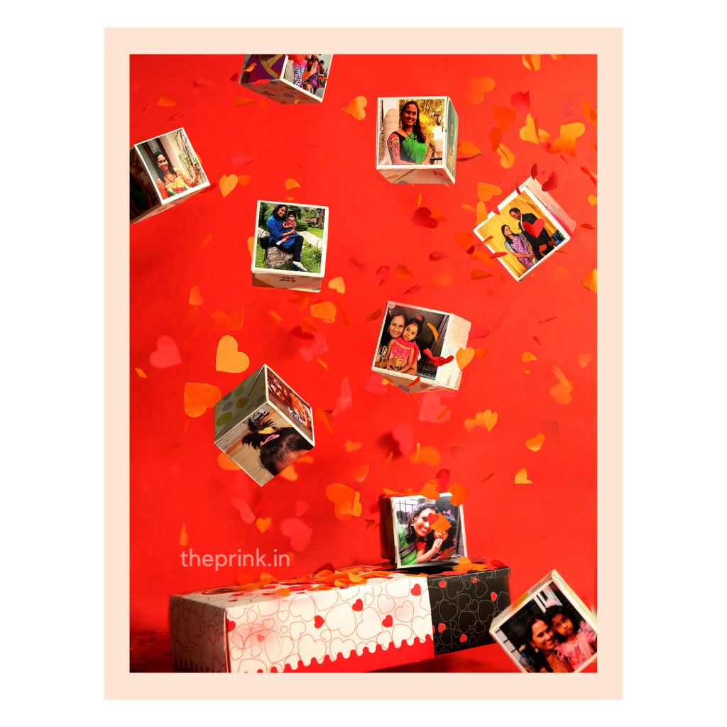 Floating photo cubes against a vibrant red background filled with falling heart confetti, conveying warmth and celebration.