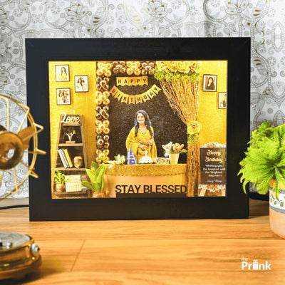 Framed art features a birthday theme with a smiling woman in yellow. Decor includes gold accents, balloons, flowers, and a 