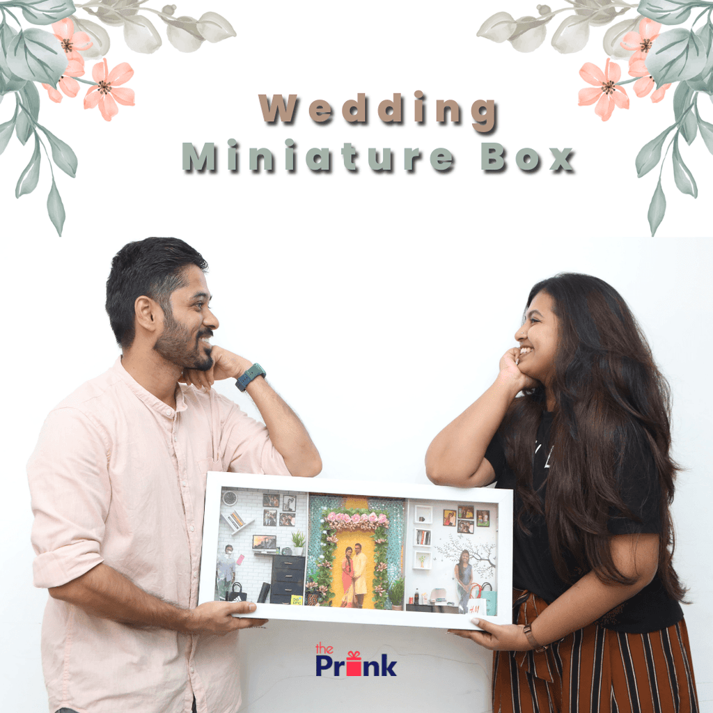 A man and a woman smiling at each other hold a framed miniature box. The title "Miniature Box" is above, adorned with floral decor, conveying a cheerful vibe.